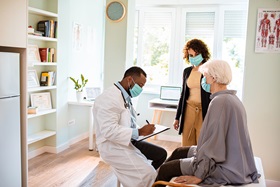 physician in lab coat talking with senior patient and spouse