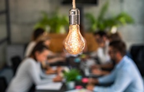 lightbulb in focus with people dining behind