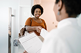 smiling woman shaking physicians hand while physician holds clipboard