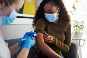 A woman gets a shot in her arm.