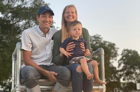 Ally Fullmer holds her son while sitting next to her husband on a lifeguard stand