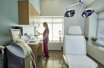 Aesthetician looking at skin care product in Penn Plastic Surgery Bryn Mawr patient exam room