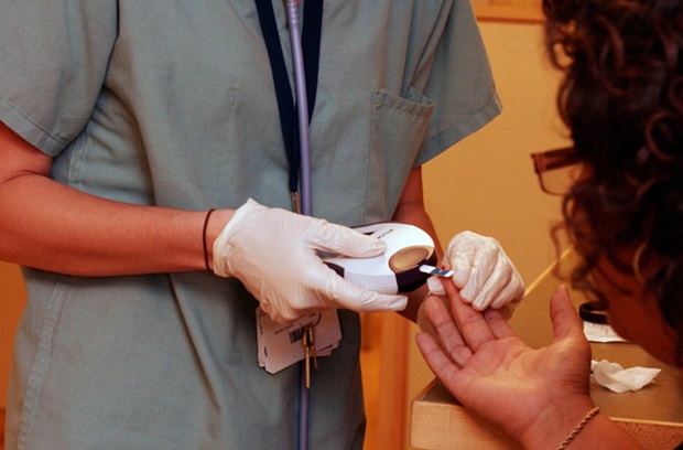 Nurse using glucose monitor on diabetes patient