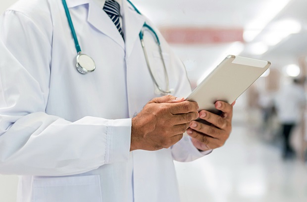 Physician holding mobile tablet for patient's health record in medical clinic 