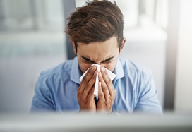 A young man blowing his nose.
