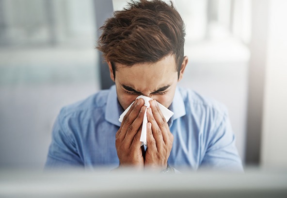 A young man blowing his nose.