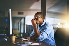 Man in front of computer with headache