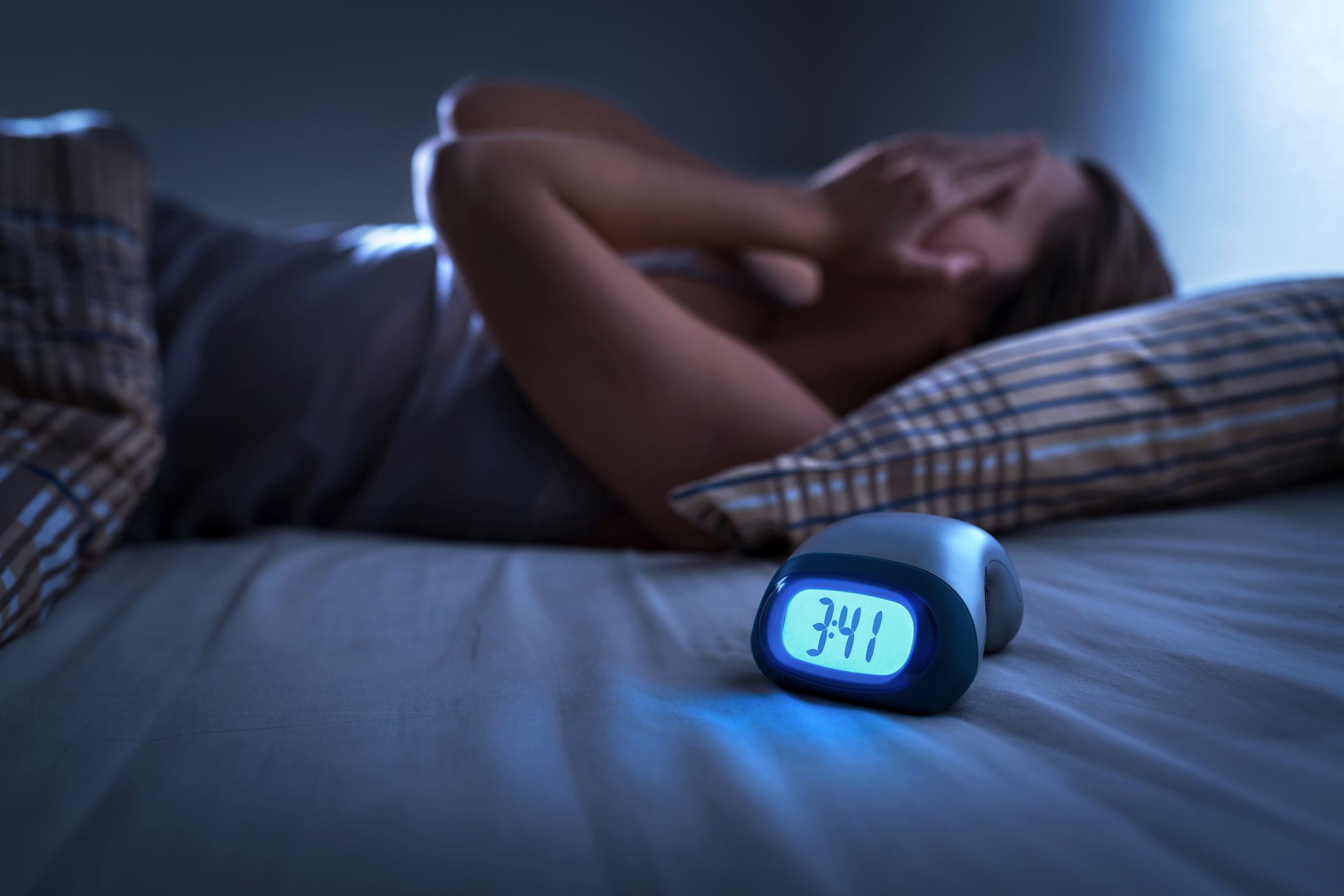 A tired woman lying awake in bed in the middle of the night.