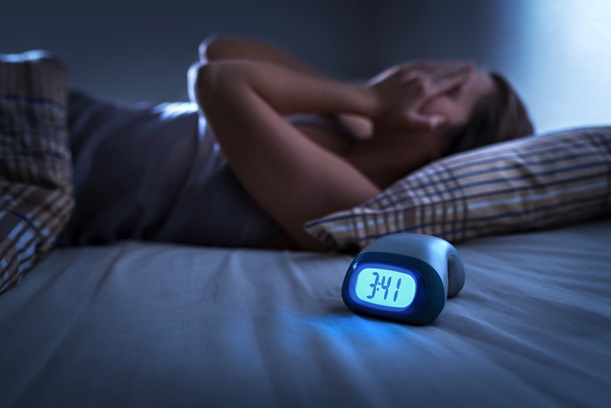A tired woman lying awake in bed in the middle of the night.