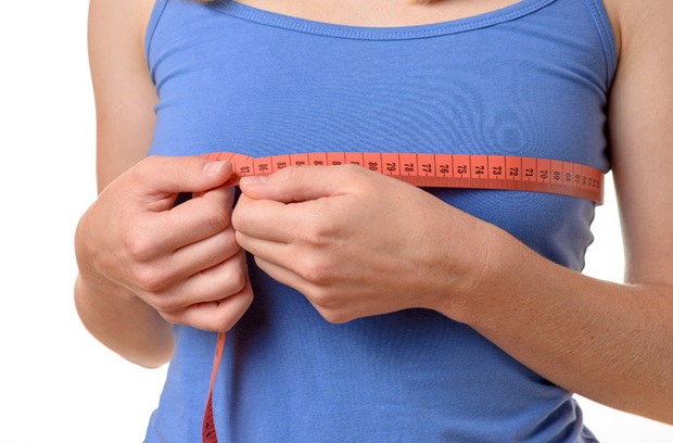 Woman using a tape measure around her bust line