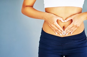 woman_making_heart_on_stomach_around_belly_button_with_hands