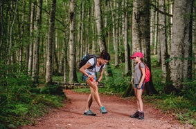 a mother and daughter spraying bug spray in the woods