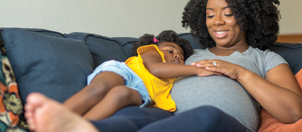 Toddler On Couch With Pregnant Mother