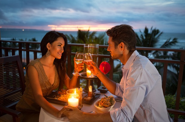 A couple out to dinner and drinking wine on a deck