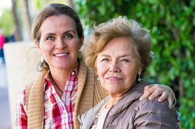 young_woman_sitting_outside_with_older_woman_both_smiling