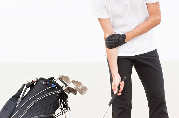 Man holding elbow in pain while golfing