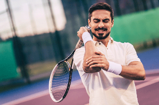 Man holding elbow in pain while playing tennis