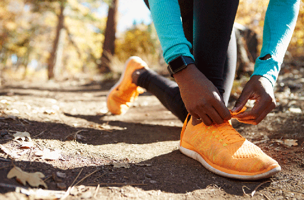 A close-up of a running tying shoe in the woods