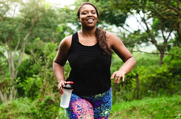 Woman running outdoors while holding a waterbottle
