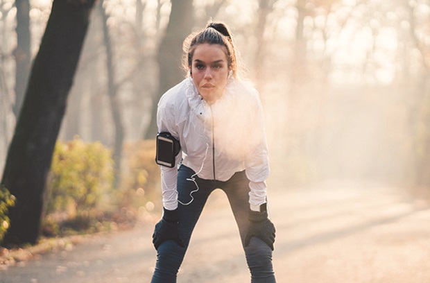 young woman stops by tree to catch breath during run