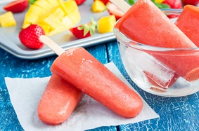 Pink, frozen popsicles on a blue picnic table