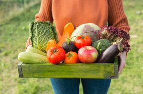 woman holding box of garden vegetables