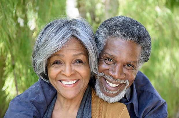 elderly_couple_outside_by_tree_hugging_and_smiling