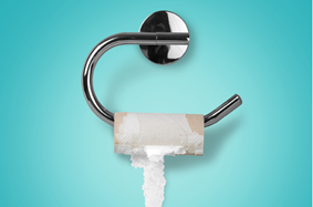 an_empty_roll_of_toilet_paper_hangs_on_hanger_in_bathroom_with_plain_light_blue_wall_as_background