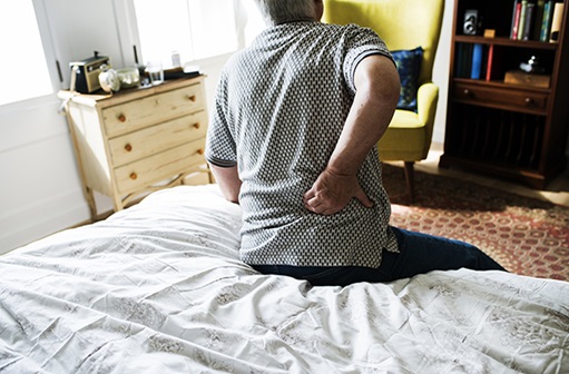 man bent over and holding back in pain