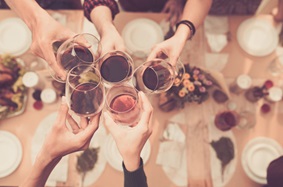 people at dinner bringing their wine glasses together