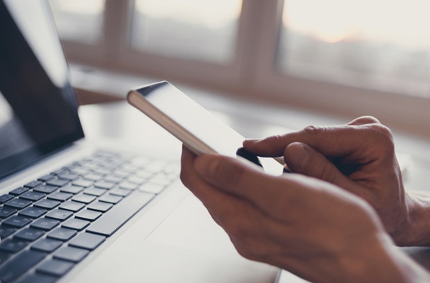 Person using smartphone and laptop