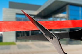 scissors cutting ribbon in front of building