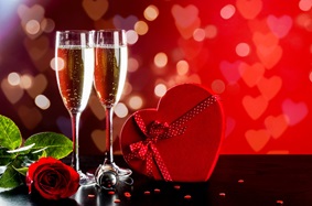 two drinks, a rose and a heart-shaped box on a table