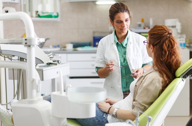woman sitting in a dentist's chair talking to the dentist