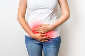 woman holding lower abdomen, which is highlighted in red