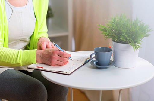 woman wearing a green sweater and writing in a planner