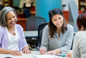 Two women smiling at a support group meeting.