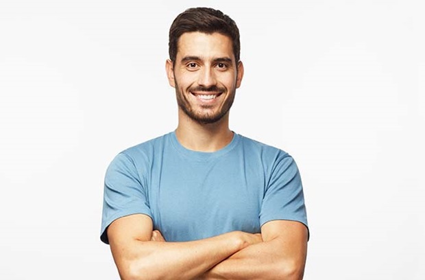 middle_aged_man_black_hair_facial_hair_folds_arm_smiles_wearing_blue_shirt