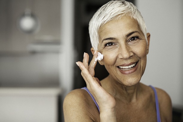 Mature woman applying wrinkle cream to her face