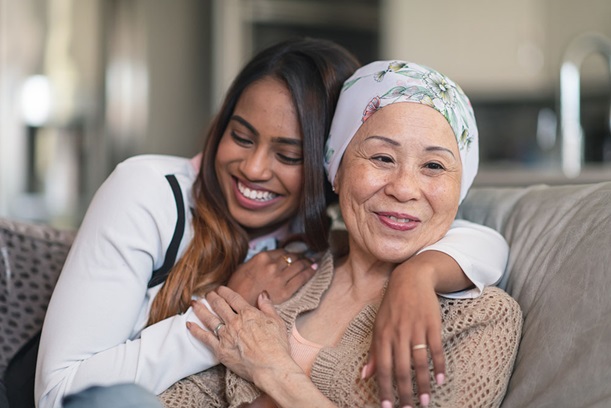 Young woman and elderly woman embracing and laughing.