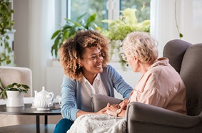 caregiver sitting next to old female patient