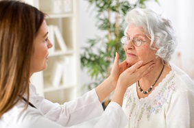 doctor examining a woman's thyroid