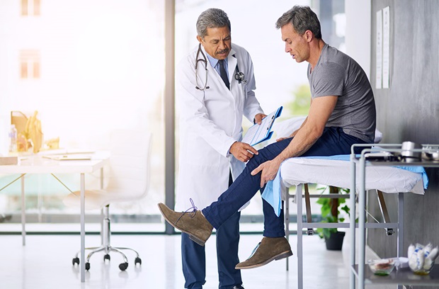 Doctor inspecting male patient's knee