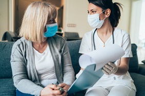 Female provider looking at paperwork with female patient; both are wearing face masks