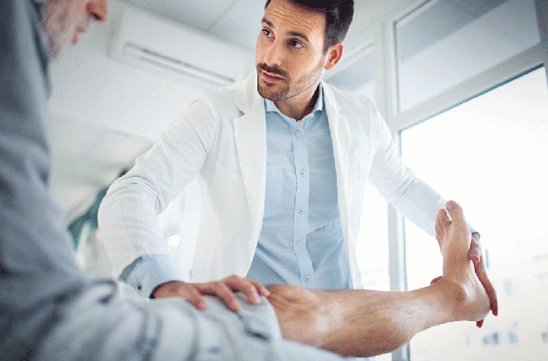 Male provider looking at patient while holding patient's foot and leg