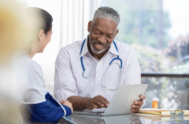 Male doctor in office with female patient wearing arm sling