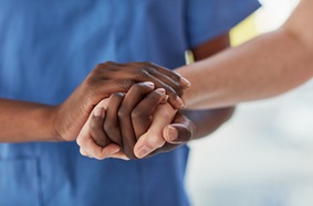A nurse holding a patient's hand