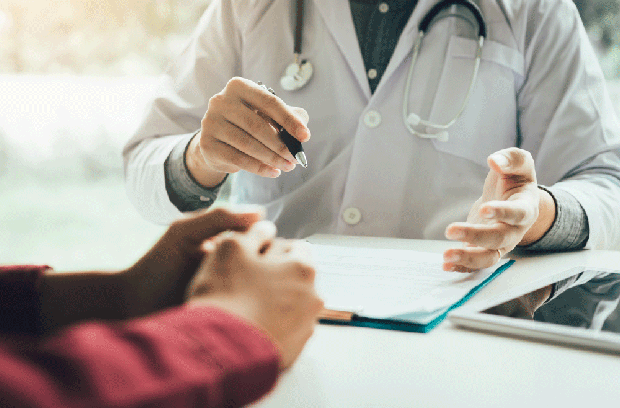 A close-up of a provider and patient talking at a desk