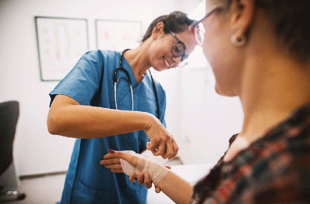Provider wrapping patient's hand and wrist with a bandage