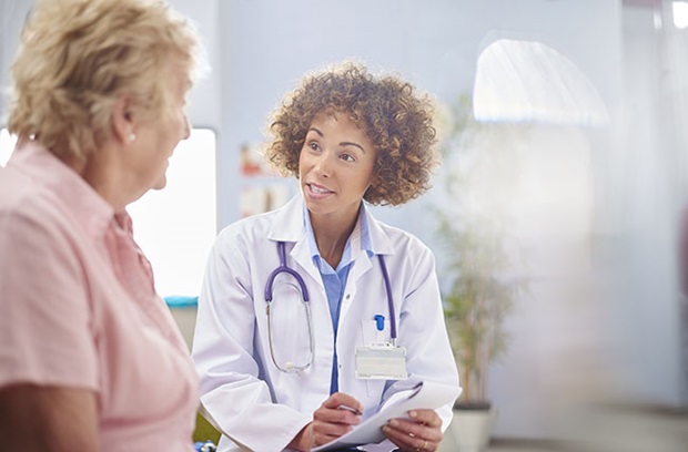 Female doctor sits and listens to a female patient.